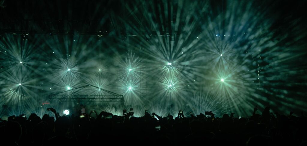 The bittersweet goodbye that saved a broken brotherhood โ wide shot of a massive outdoor music festival crowd with laser lights at night