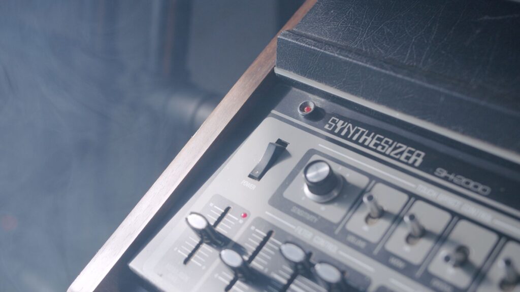 The robot who walked away from the machine — analog synthesizer knobs close up hands studio