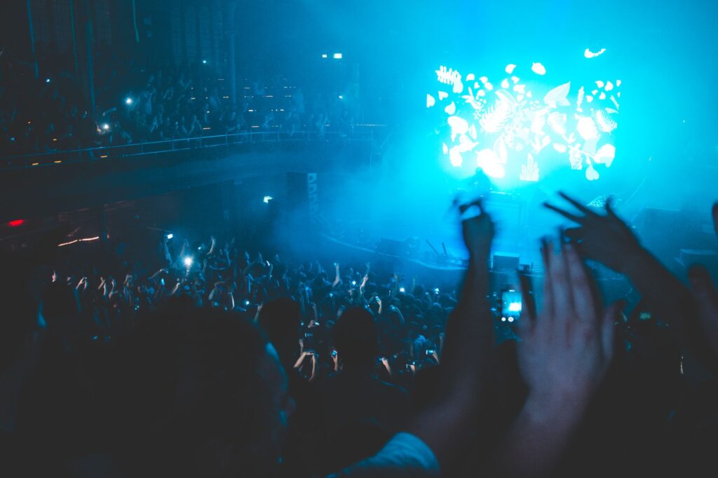 Why Tiësto's Adagio for strings still saves the dancefloor — dark sweaty warehouse rave crowd hands up strobe lights