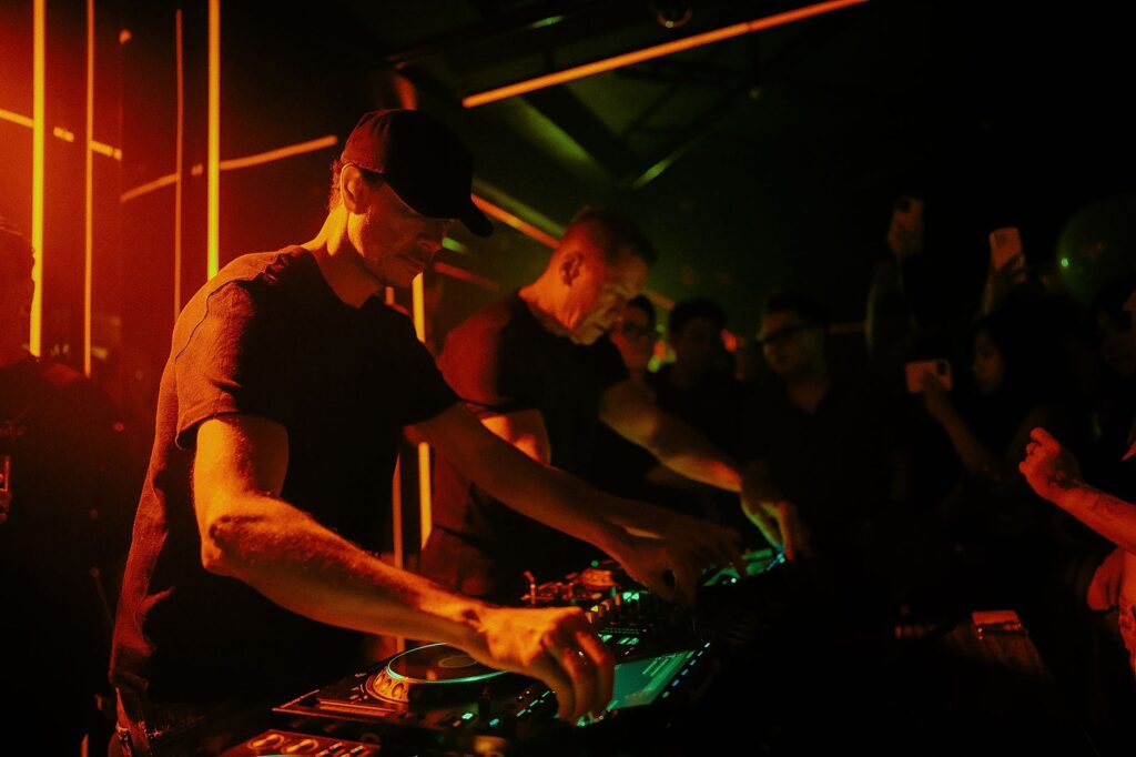 Why Born Slippy .NUXX is still our beautiful defiance — gritty underground techno club dj booth silhouette smoke