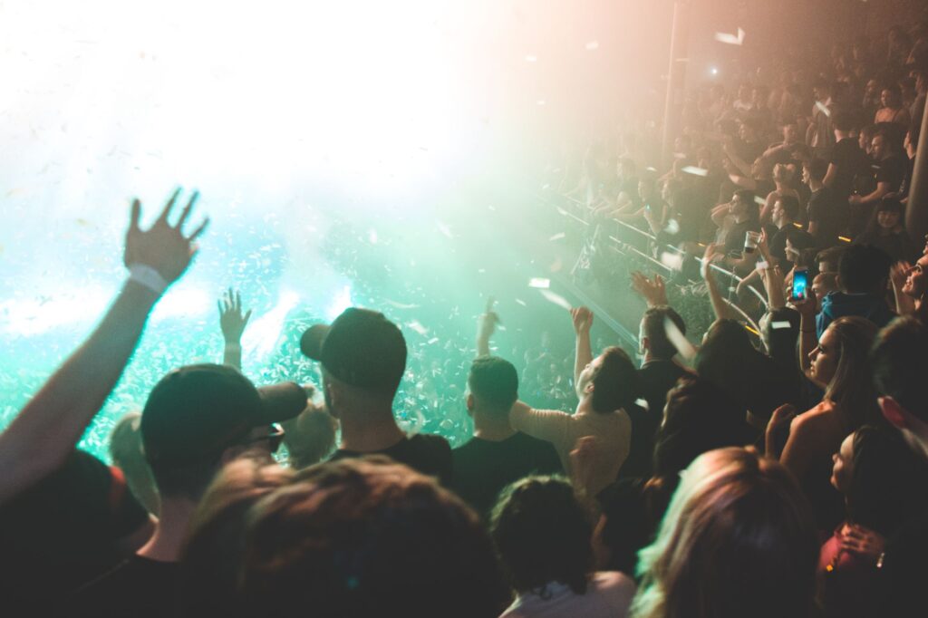 Why Born Slippy .NUXX is still our beautiful defiance — sweaty dark warehouse rave crowd dancing hands up strobes